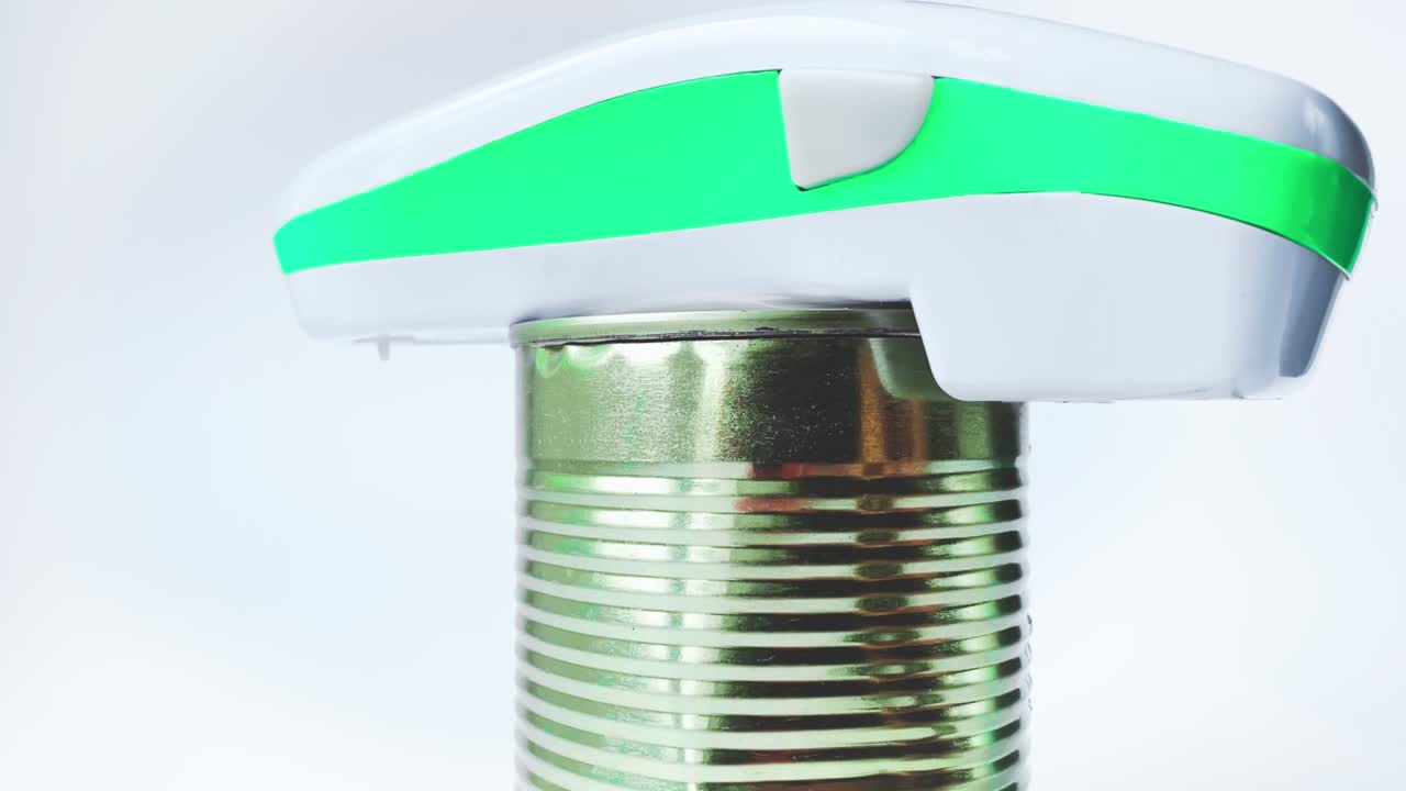 Close up of electric can opener and canned goods on white background
