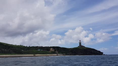 Lighthouse-at-the-edge-of-the-island-in-Batanes,-Philippines---shot-from-a-moving-boat
