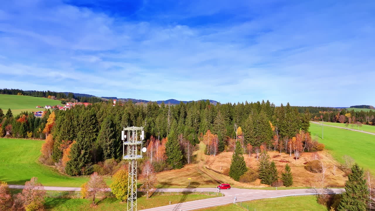 Going up near the radio tower standing in the meadow. Reveling aerial view on the wood and rural residential area in Weitnau, Bavaria, Germany