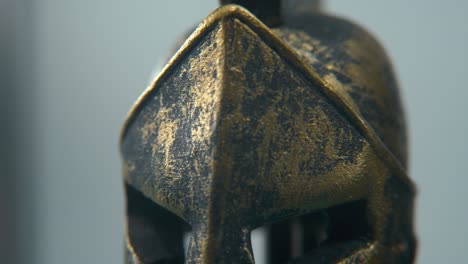 a close-up macro detailed shot of a spartan design, two different ancient warrior metal bronze top of the helmets, glowing textured shapes, studio lighting, 4k cinematic video, slow motion, pan right