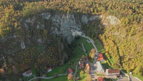 Panorama-Drohnenaufnahme-Der-Burg-Predjama-Mit-Bewegung-Von-Rechts-Nach-Links-Bei-Sonnenuntergang