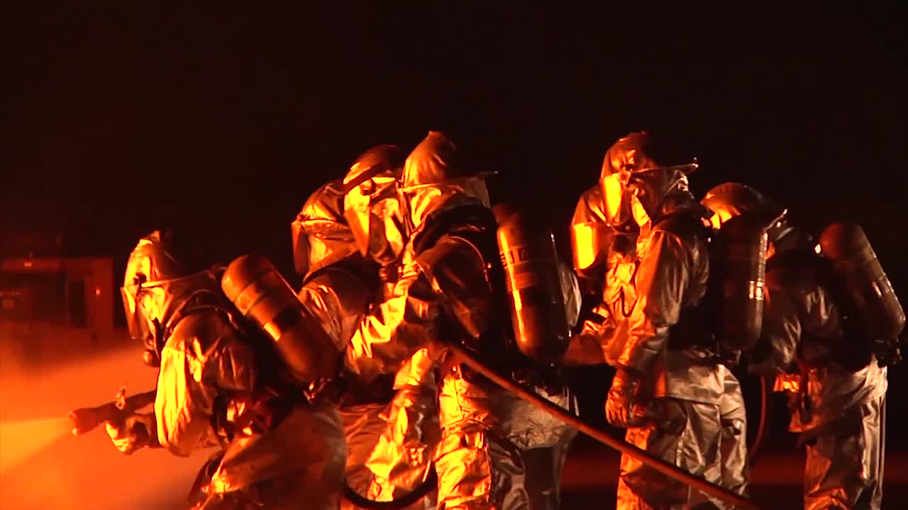 방호복 또는 내열복을 입은 소방관이 밤에 격렬한 화재를 진압합니다 1