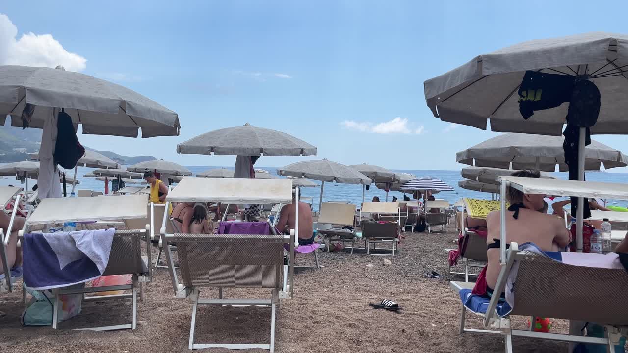 Sole e pioggia su una spiaggia in Montenegro, molti turisti in una splendida località.