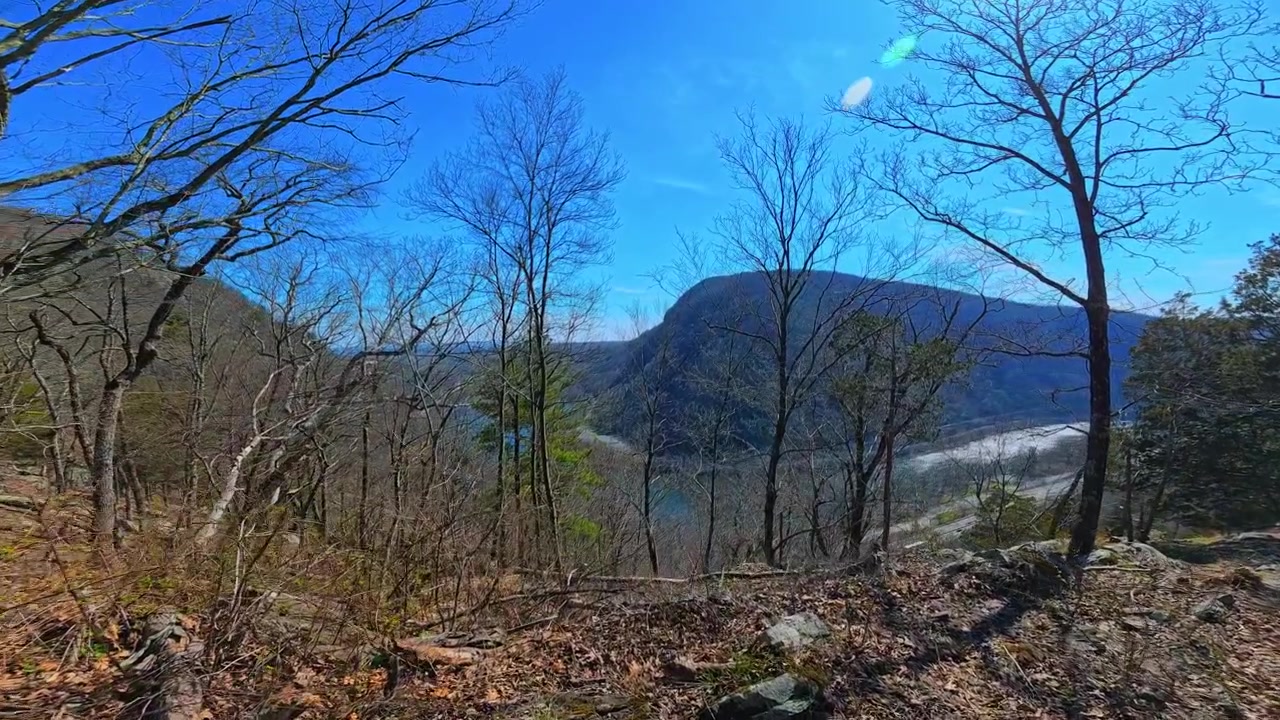 Panoramisk bjergudsigt fra Mount Tammany's klippefyldte top. Bred udsigt over skovklædte bjergrygge og klar blå himmel fra et højtliggende klippeplateau