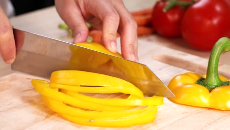 manos cortando pimientos con tomates en el fondo