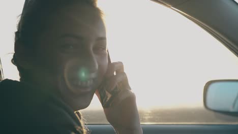 nice woman sits in car and talks to friend holding telephone