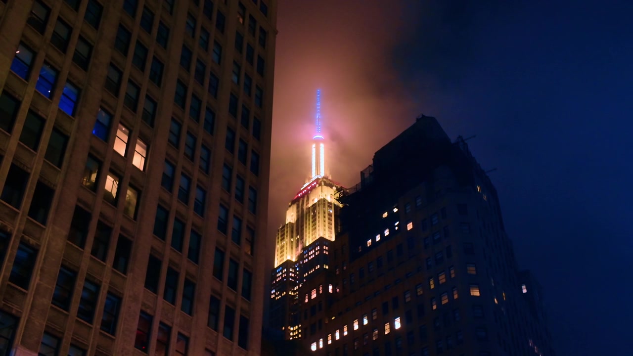 Empire State Building che risplende nella notte nebbiosa. L'Empire State Building si erge attraverso la nebbia di notte a Midtown Manhattan con un'illuminazione suggestiva.