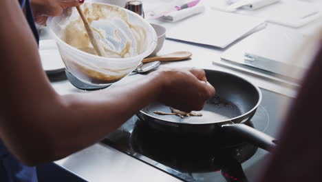 close up of female teacher adding flatbread mixture to pan in cookery class