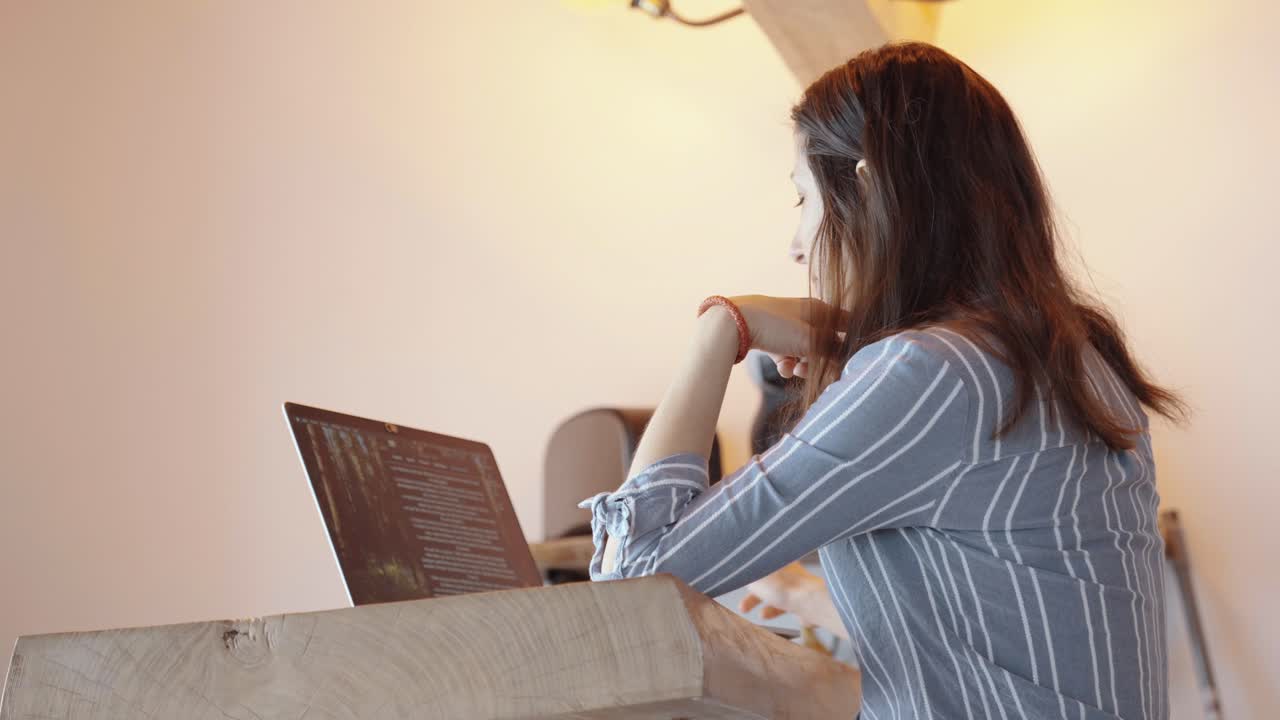 Woman working on a laptop in a minimalist home office, symbolizing focus and productivity. Calm and concentrated environment with neutral tones, clean setup, and soft lighting