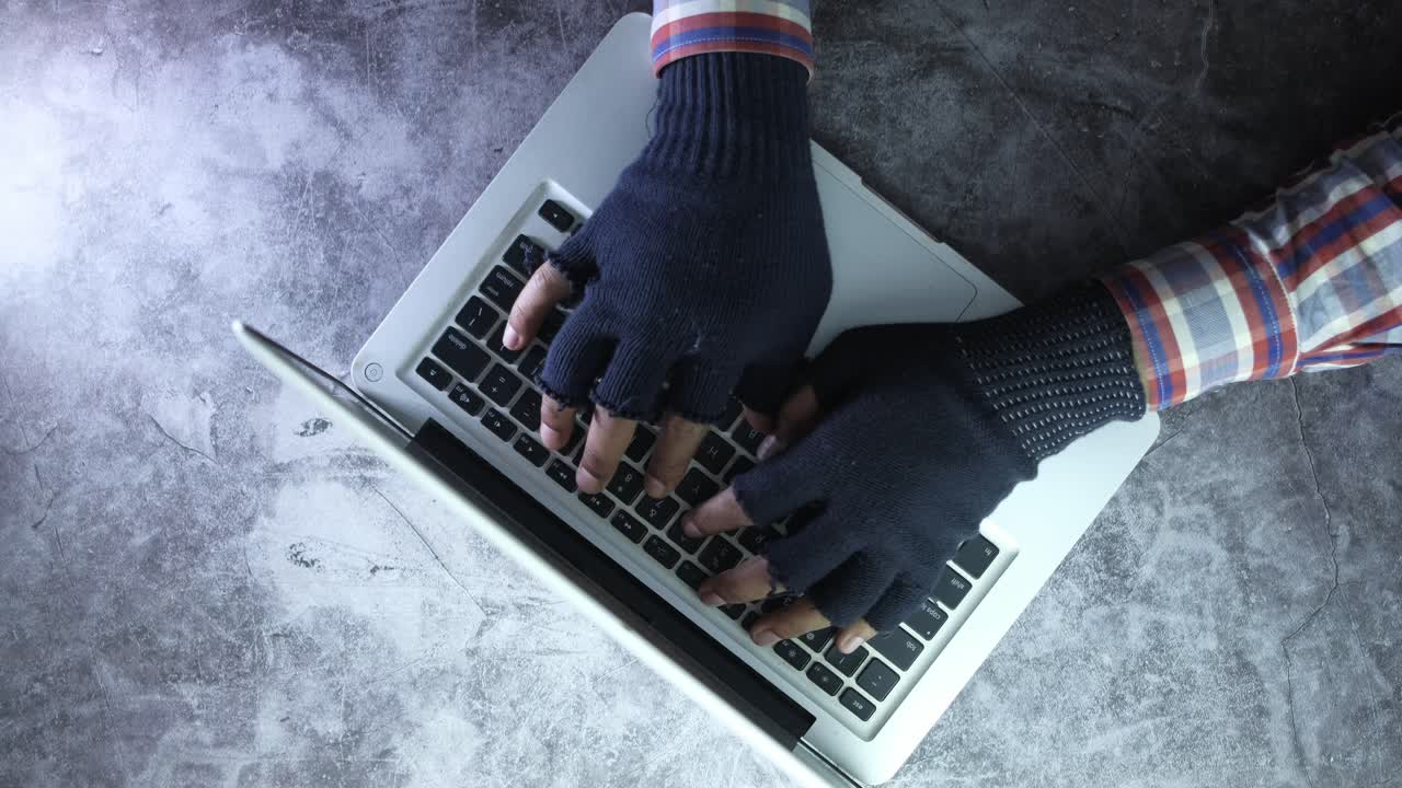 장갑 을 착용 한 사람 이 노트북 에 타이핑 하고 있다