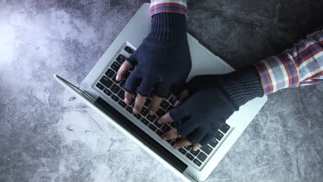 Person with gloves typing on a laptop