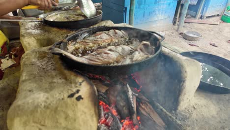 preparing fried fish on a rustic stove with firewood and oil on a dominican beach