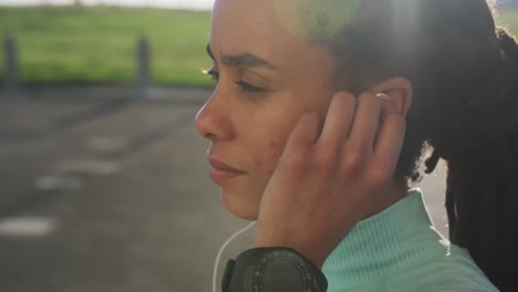 african american woman in sportswear wearing earphones on a sunny day