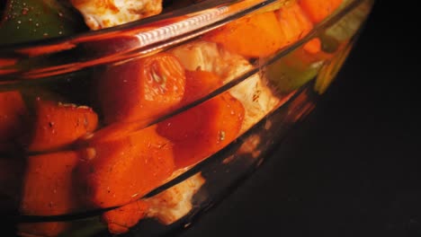 medley of grilled vegetables in a glass dish against black background