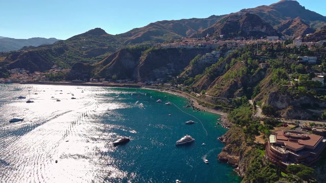Italia Sicilia, ripresa aerea con drone in dolly out del Golfo di Naxos a Taormina e del Capotaormina Cliff Resort.