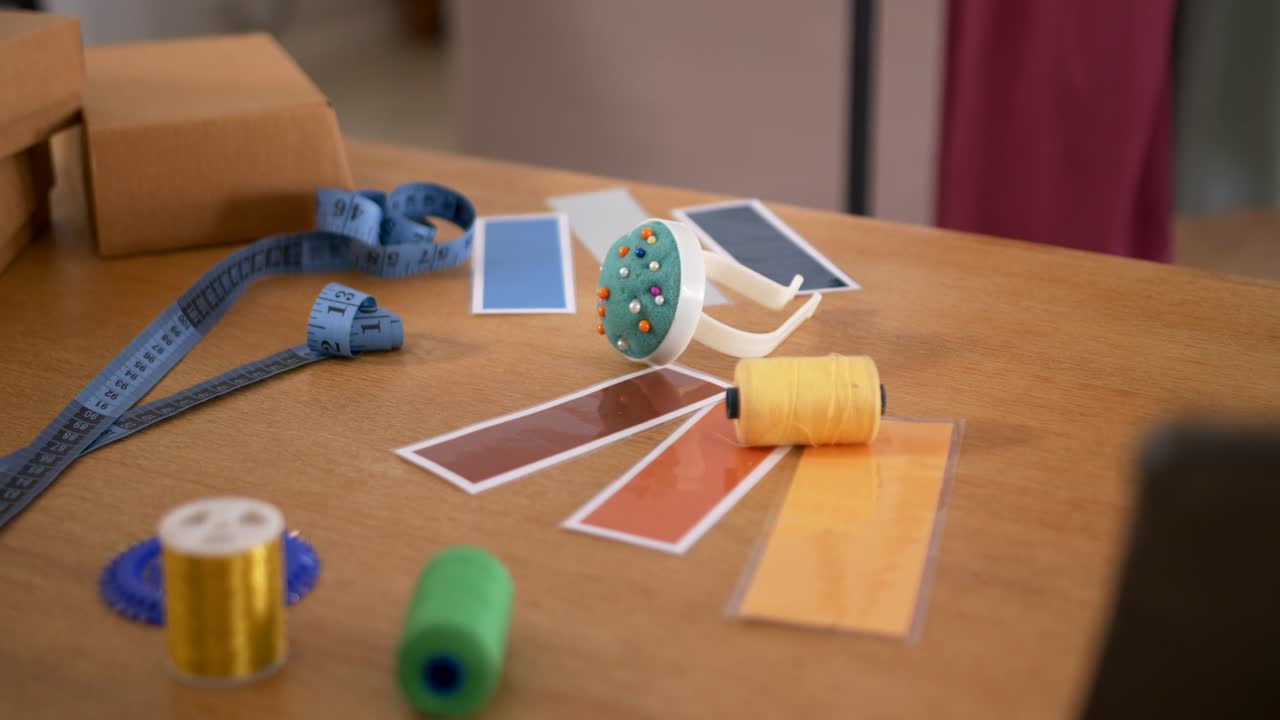 Camera pulling focus and shifting framing on wooden table, highlighting yellow spool pincushion