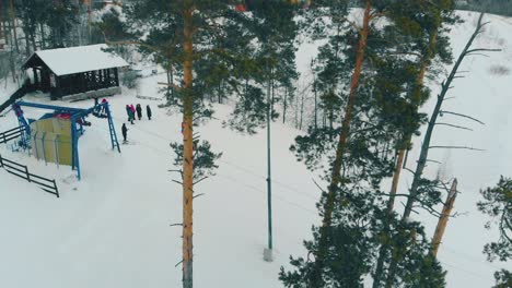 la gente se encuentra en la cima de una colina junto a la estación de elevación en el bosque de pinos.