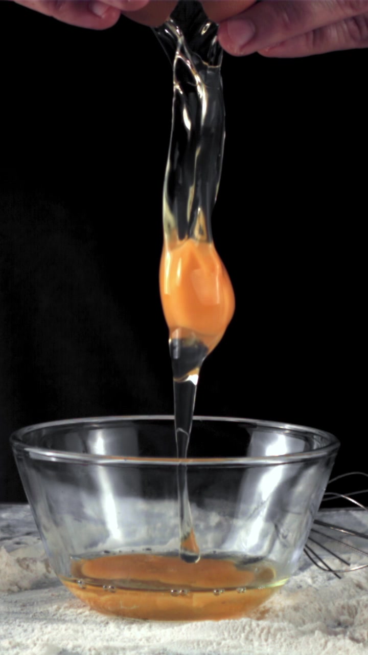 Slow Motion of Hands Cracking an Egg into a Glass Bowl