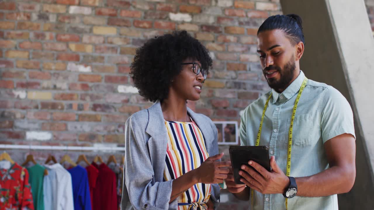 diversos diseñadores de moda masculinos y femeninos en discusión en el trabajo mirando la tableta