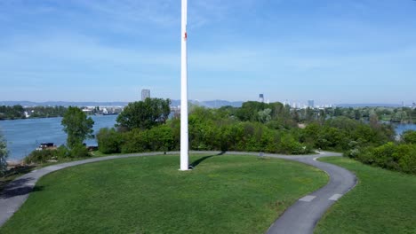 pedestal drone shot of a windmill standing in the middle of a park in danube island in vienna, austria