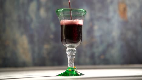 clip de vino tinto en bucle sin costuras que se vierte en un vaso rústico con fondo azul