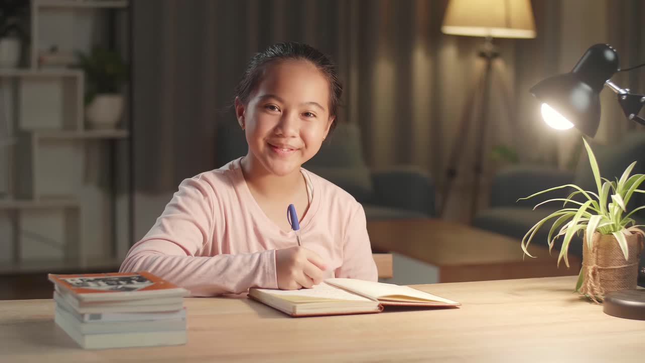 Portrait Of Asian Girl Is Studying At Home, Asia Child Happiness And Smile Confidently While Sitting On The Table At Night