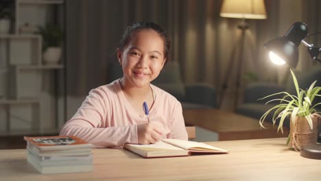 portrait of asian girl is studying at home, asia child happiness and smile confidently while sitting on the table at night