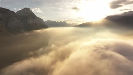 aerial view of a breathtaking fog-covered walensee lake in switzerland, bathed in the warm glow of the morning sun.