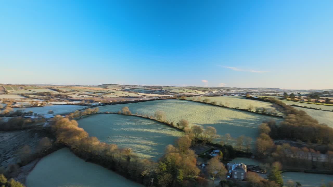 hermoso paisaje ondulado de colinas congeladas y líneas de árboles en el campo irlandés temprano en la mañana en invierno