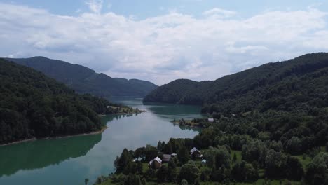 aerial shot of the mountain forest meeting the clean lake of paltinu of doftana valley in romania