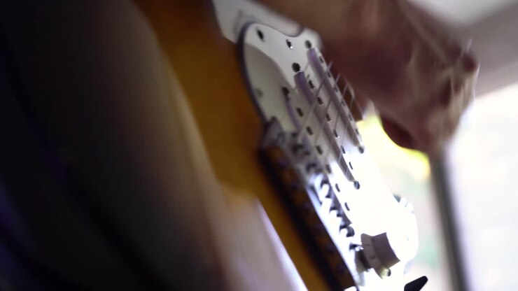 Müzisyenin elektrik gitarını çalarken ellerinin alçak açı çekim detayı