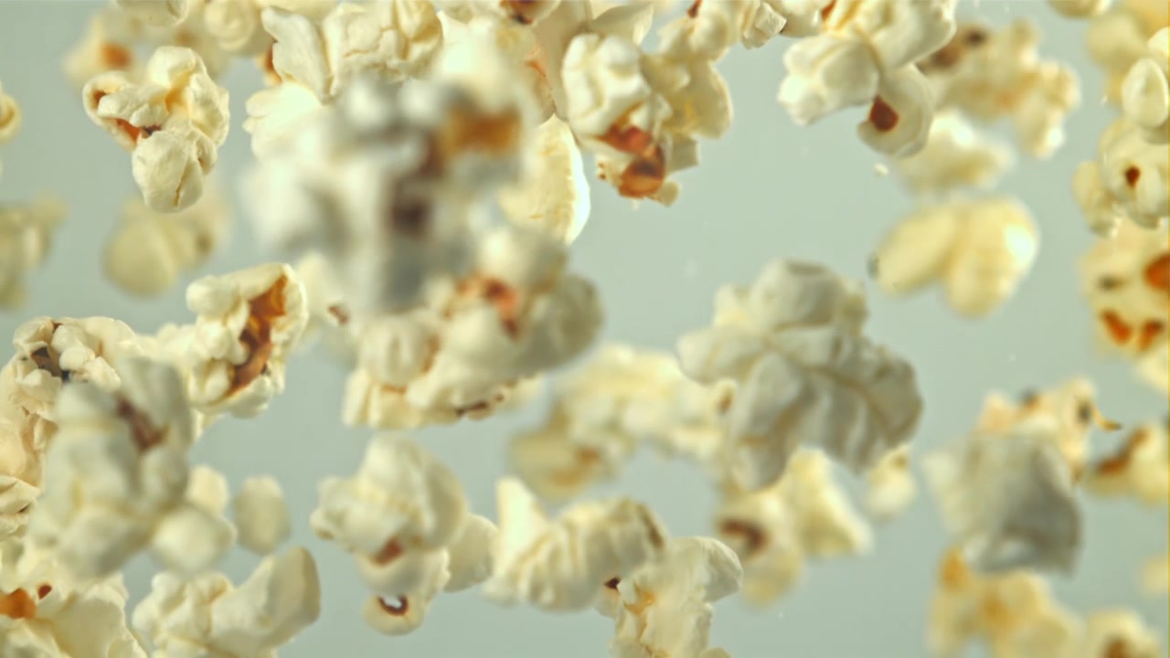Popcorn che cadono al rallentatore su sfondo bianco