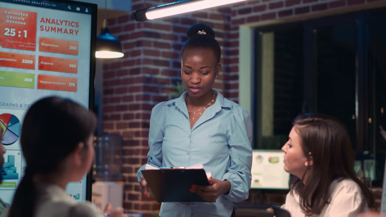 Businesswoman giving presentation in meeting, holding clipboard, reading report