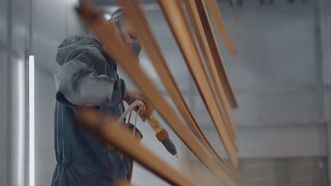 molar man sprays paint on steel profiles in a respirator mask and protective suit in slow motion