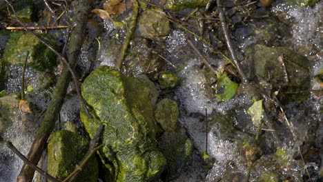 small stream running across mossy rocks in slow motion