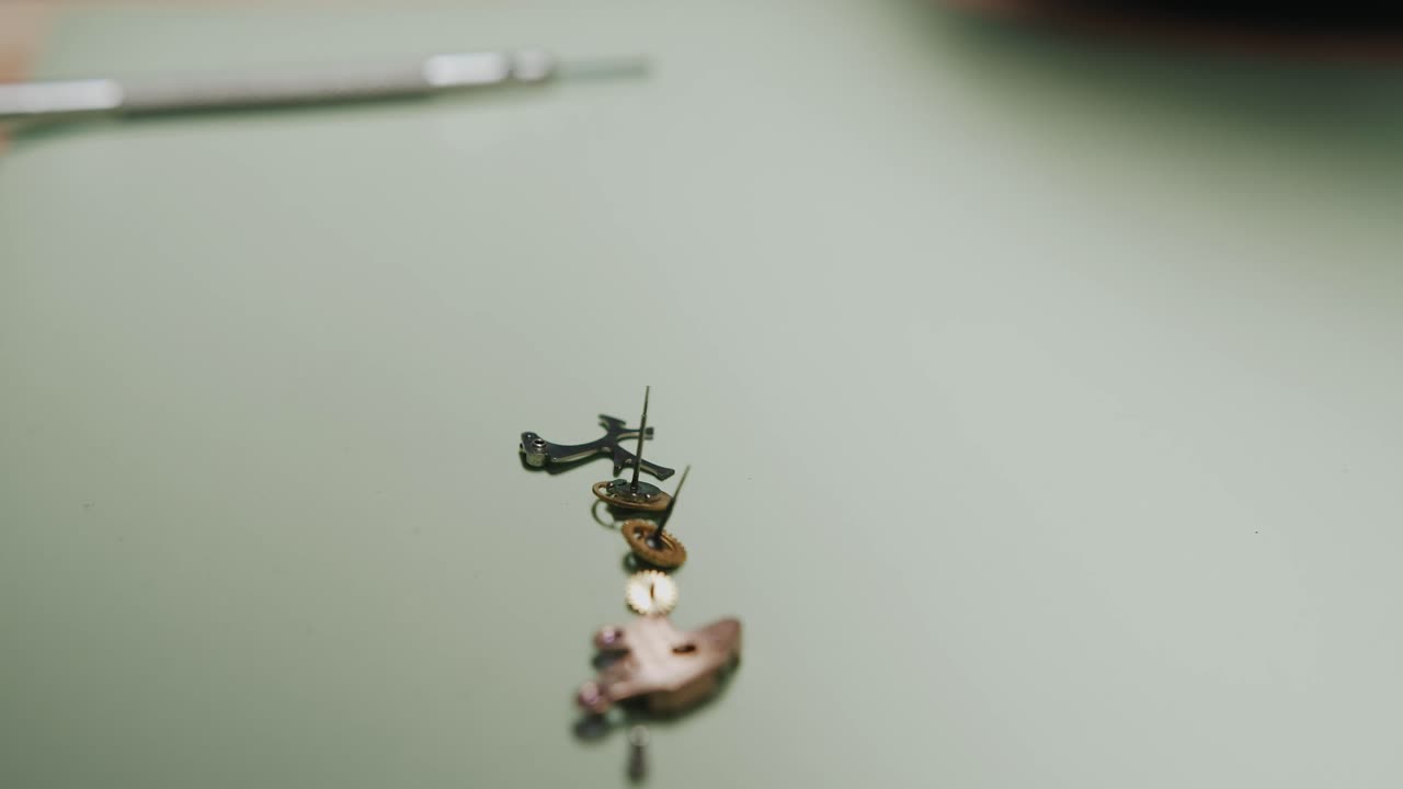 Primo piano di un orologiaio che smonta i pezzi di un orologio da polso per riparazione e pulizia.
