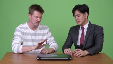 젊은 아시아 사업가와 젊은 스칸디나비아 사업가가 노트북으로 함께 일하고 있습니다.
