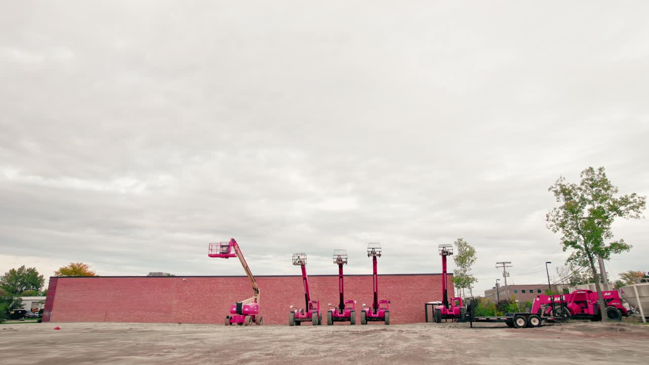 Distancing video from construction equipment, red colored telescopic boom lifters, design gives the vertical reach needed to access overhead jobs