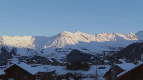 在阿爾卑斯山的滑雪場上,在山頂上夕陽的時光<unk>移,前景是村莊