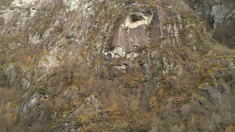 Toma-De-Drone-Acercándose-A-Una-Pared-Rocosa-En-El-Pueblo-De-Cavergno,-En-El-Distrito-De-Vallemaggia,-Cantón-De-Ticino,-En-Suiza.