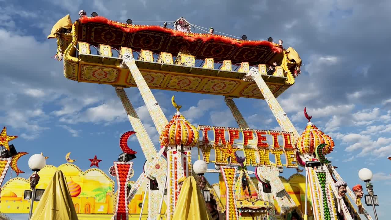 遊園地のフライング カーペット アトラクションで、子供 1 人を乗せて移動