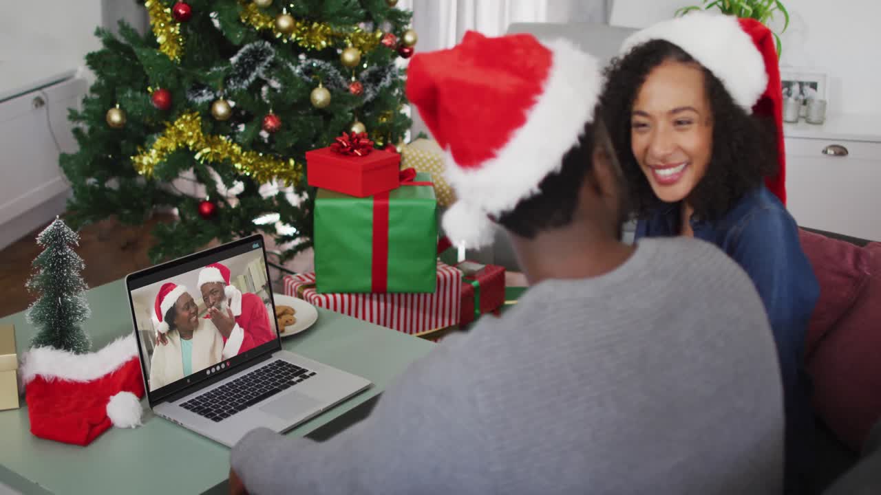 feliz pareja afroamericana en videollamada en computadora portátil con pareja mayor en tiempo de navidad