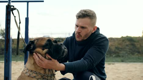 joven deportivo abrazar y jugar con su perro bullmastiff al aire libre en la naturaleza
