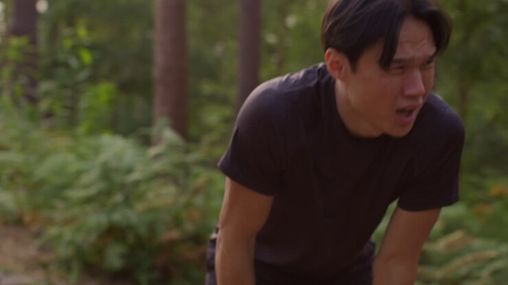 Close Up Of Tired Mid Adult Man Exercising Doing Work Out Outdoors Running Along Track Through Forest Stopping To Catch Breath Shot In Real Time 1