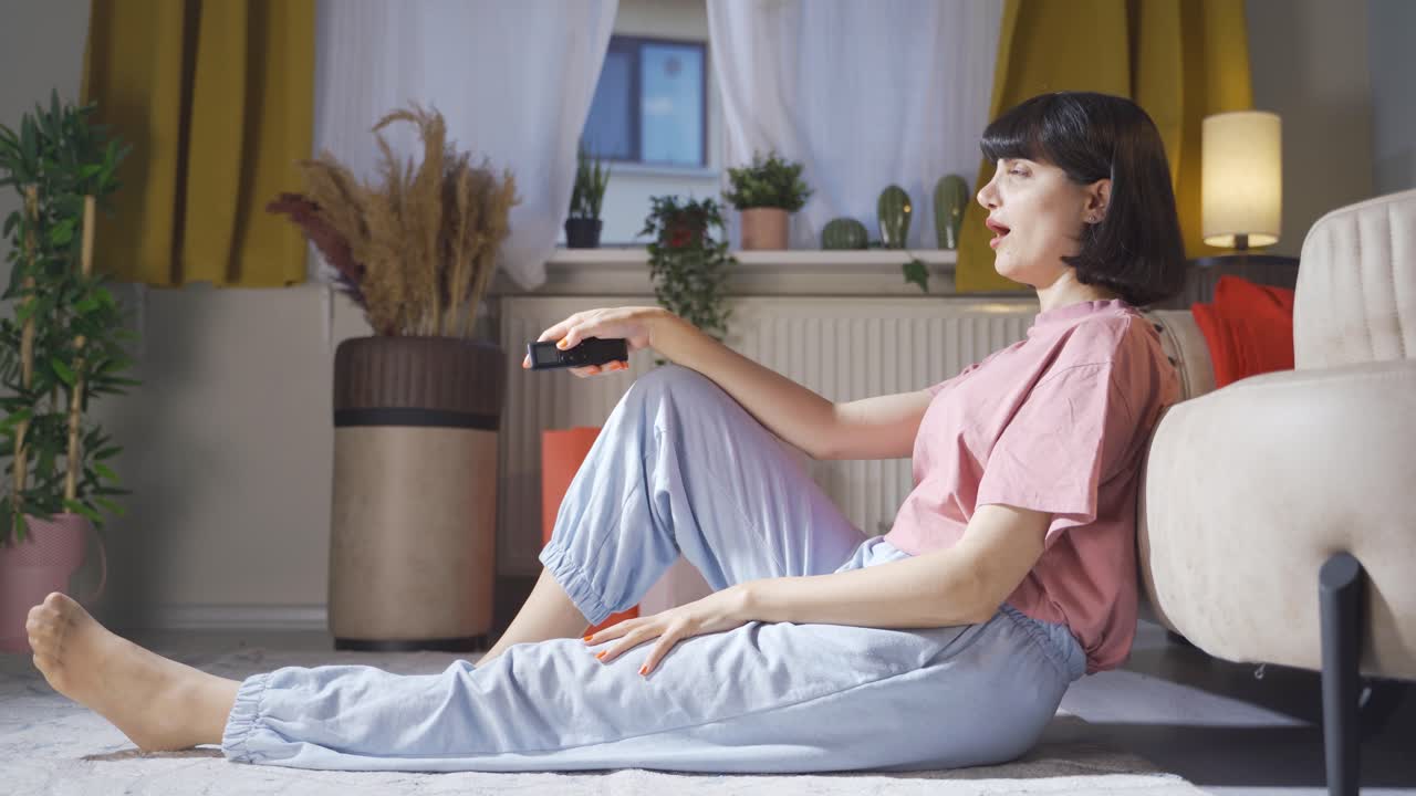 놀라서 텔레비전을 쳐다보는 여자.