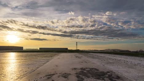 reveal of winter sunset over industrial area with snow covered field, czechia