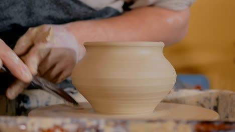 professional potter carving pot with special tool in pottery workshop