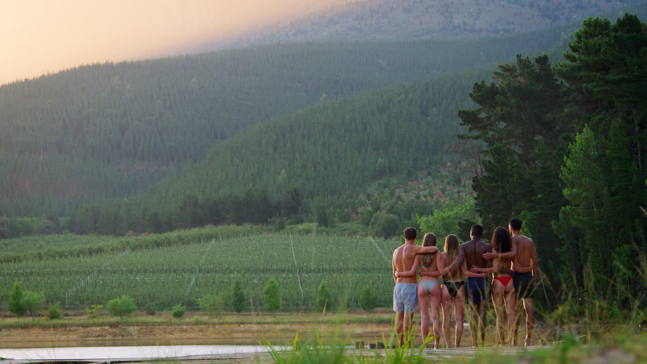 взрослые друзья на причале в озере, задний вид, право кадра