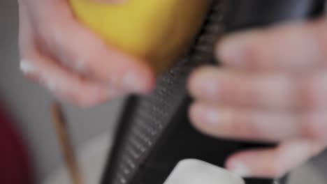 Grate-fresh-lemon-peel-cooking-tasty-pie-at-home-traditional-kitchen-during-the-day-close-up-detail-shot