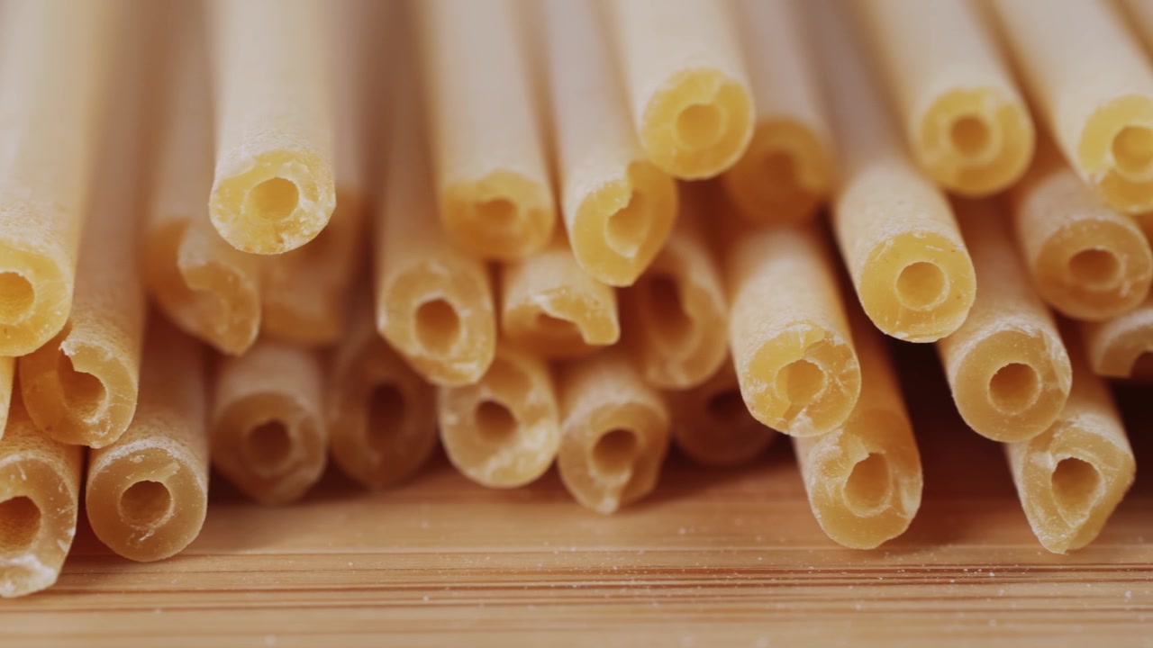 Primo piano di bucatini crudi su una superficie di legno